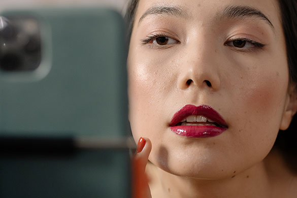 Close-up of woman with red lipstick holding a phone and looking into it