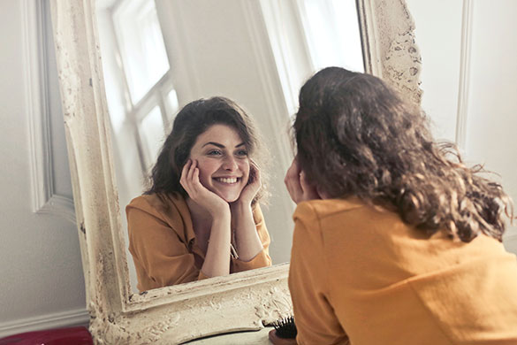 Woman smiling looking in the mirror and holding her face