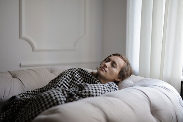 Woman sleeping with blanket on a single seater couch