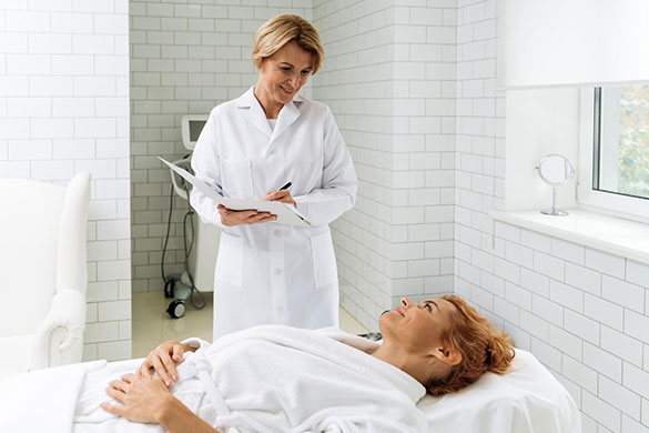 Woman lying down on clinic bed consulting medical professional