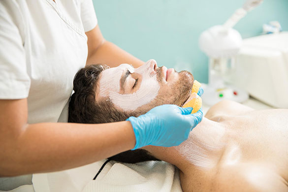 Man receiving facial treatment with eyes closed