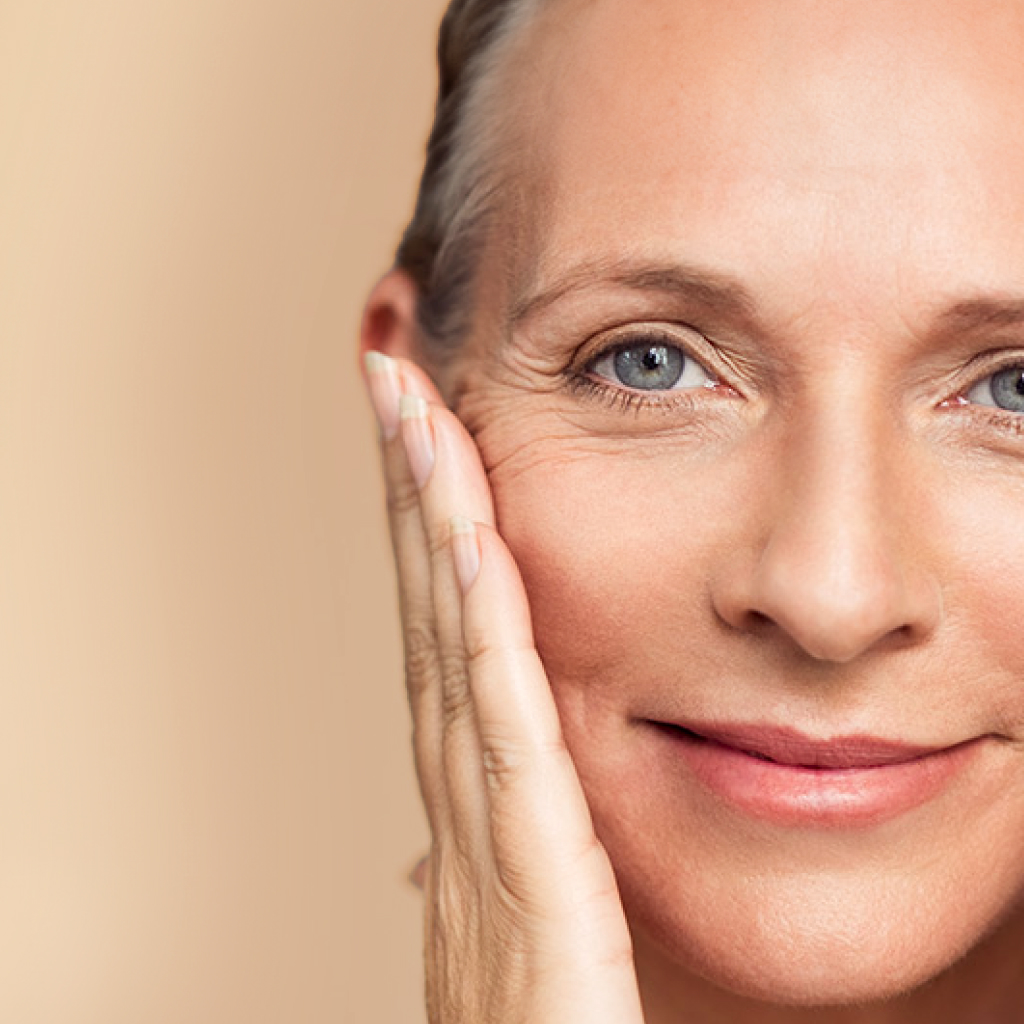 women with wrinkles touching her face on beige background