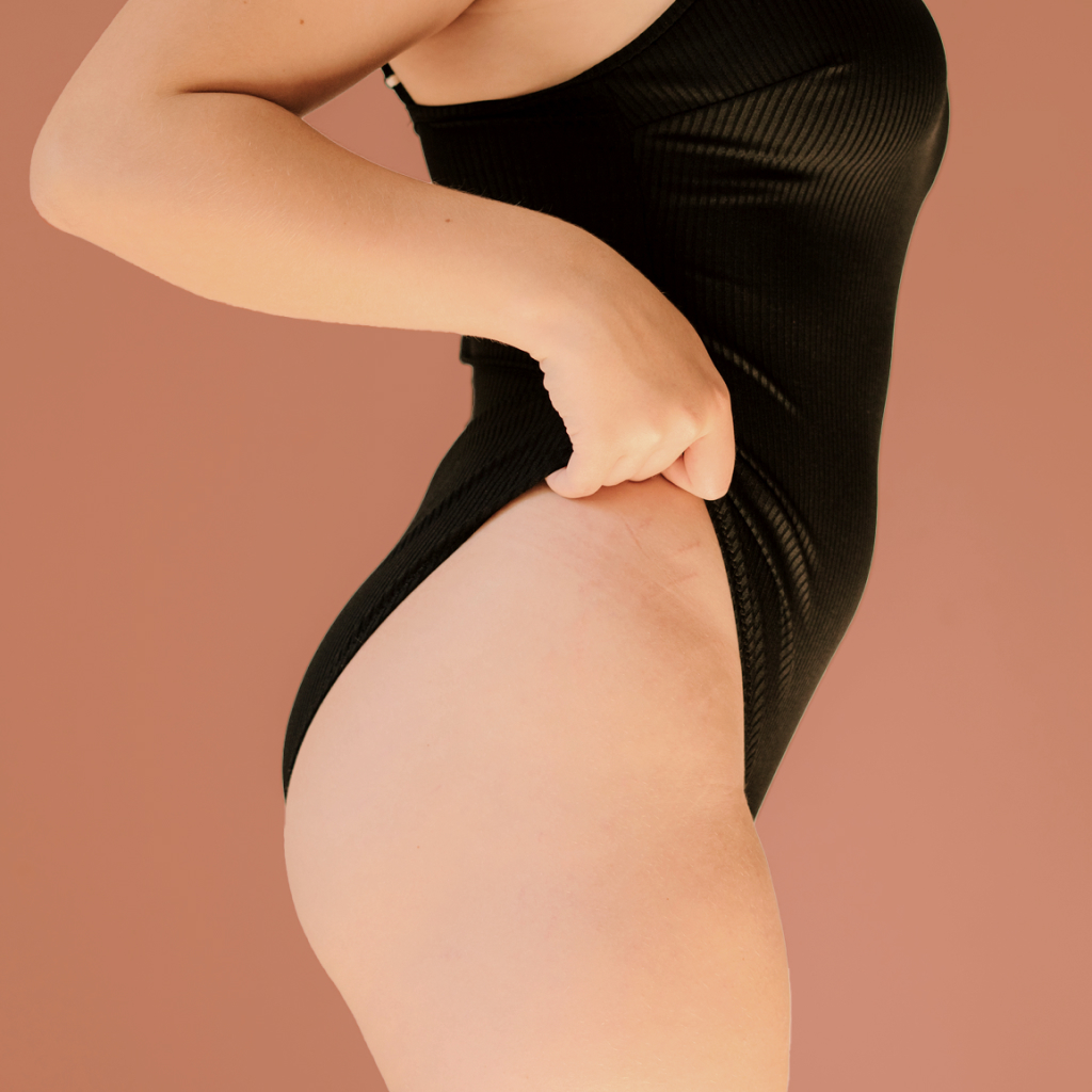 side profile of a women in a black body suit with her thigh exposed
