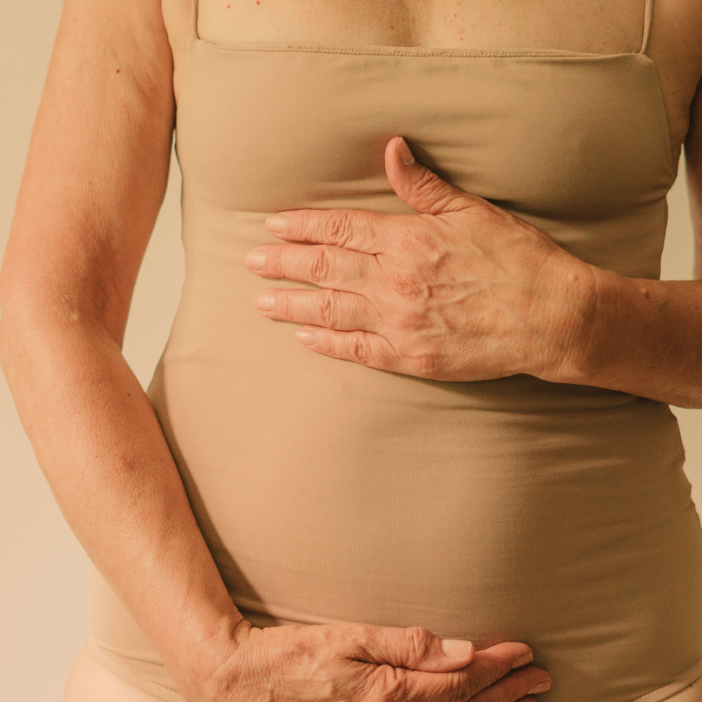 feminine figure in beige undergarments clutching stomach