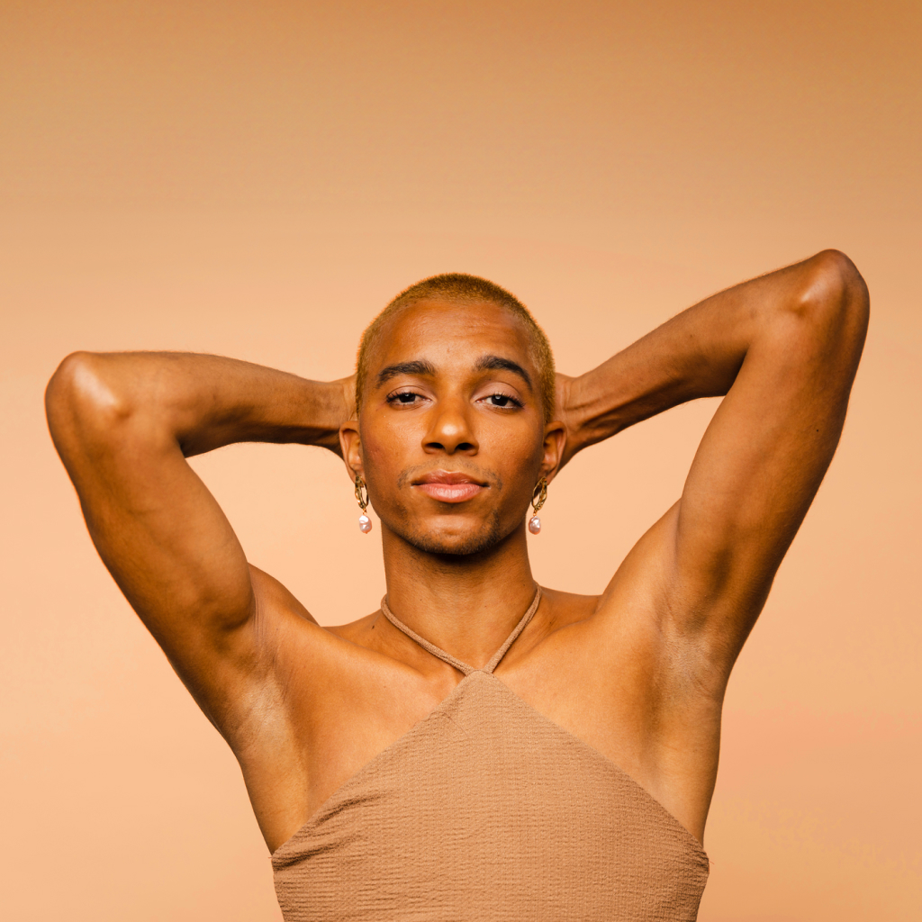 confident person with their arms behind head in brown body suit on a beige background