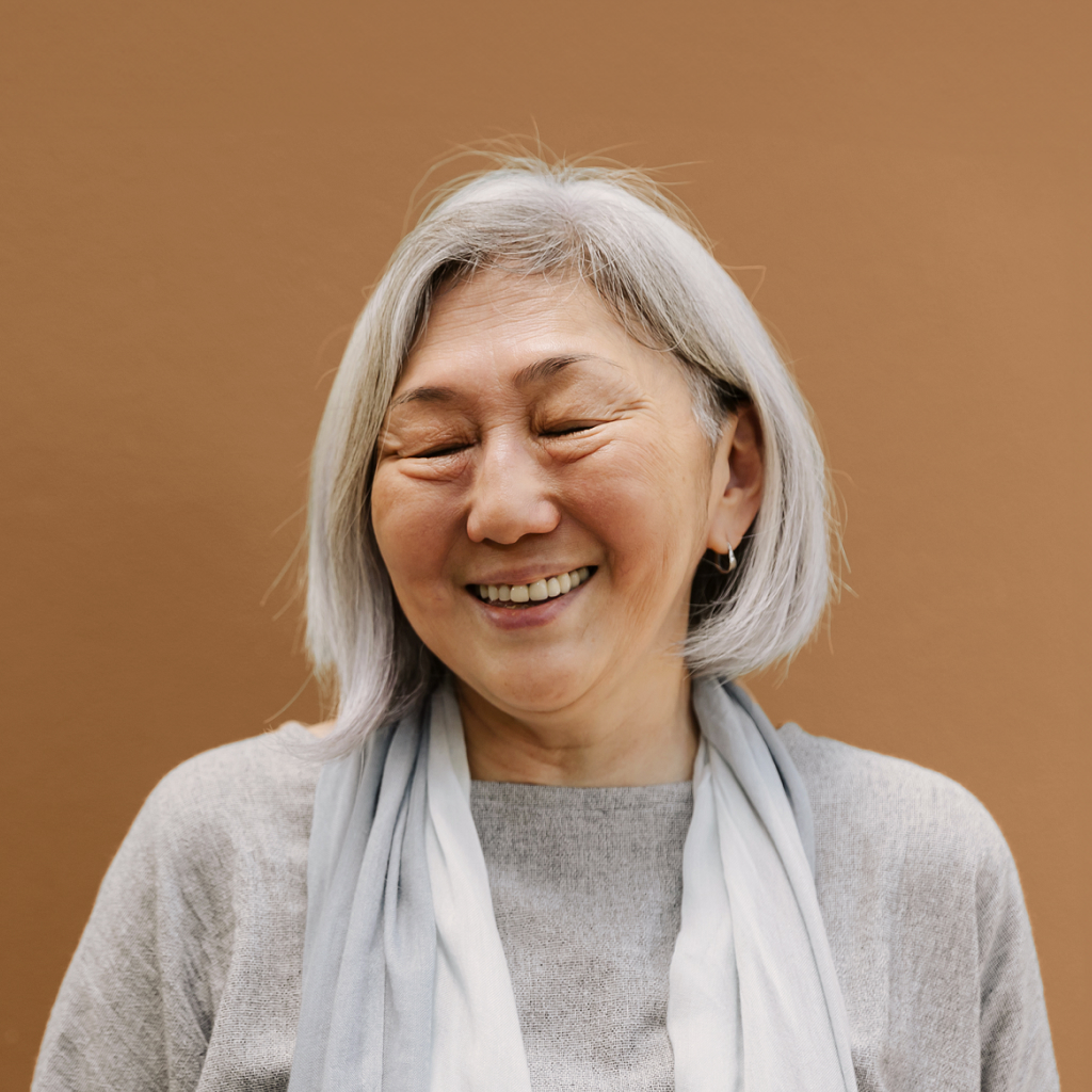 picture of women with grey hair with eyed closed against brown background