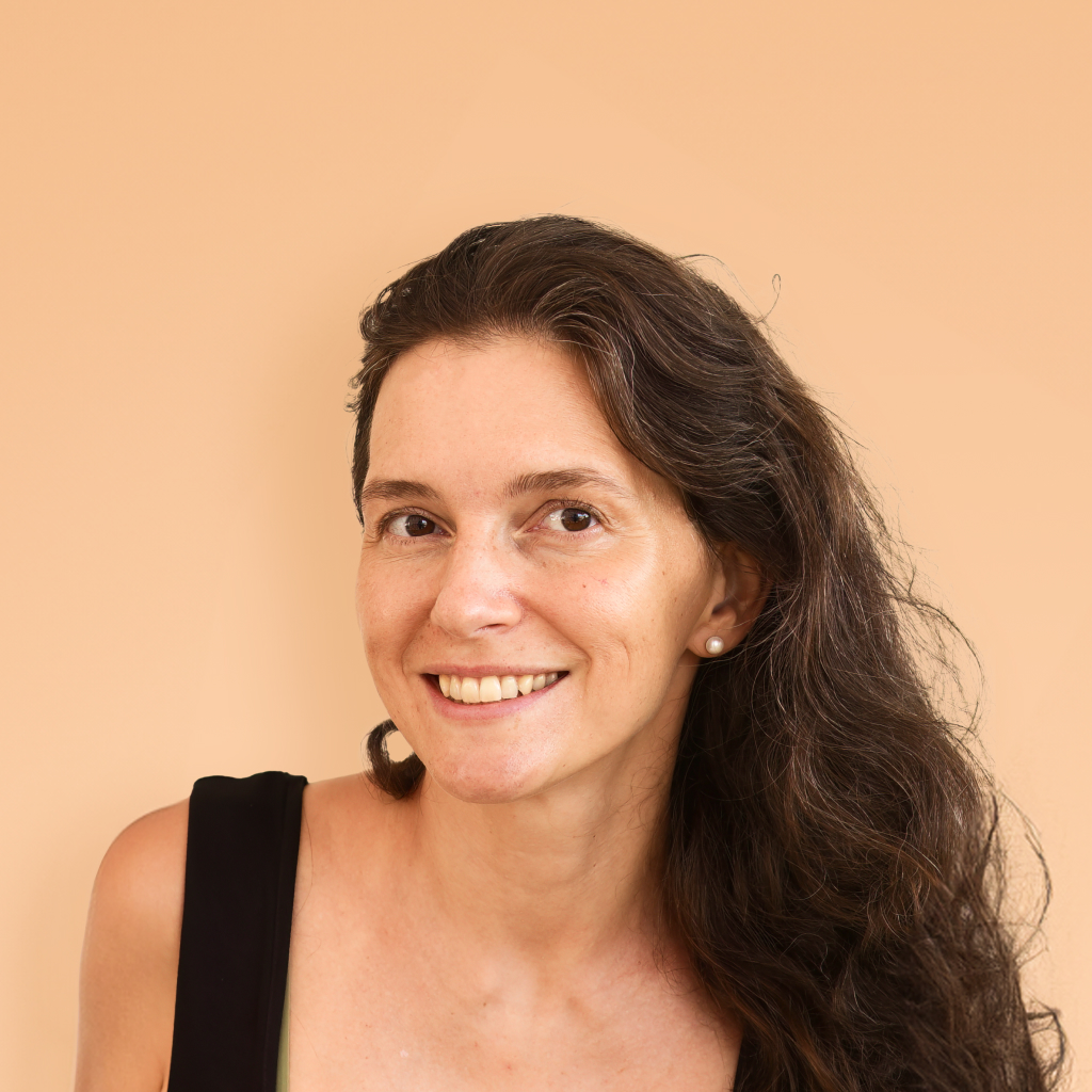 women with dark hair smiling on a cream background