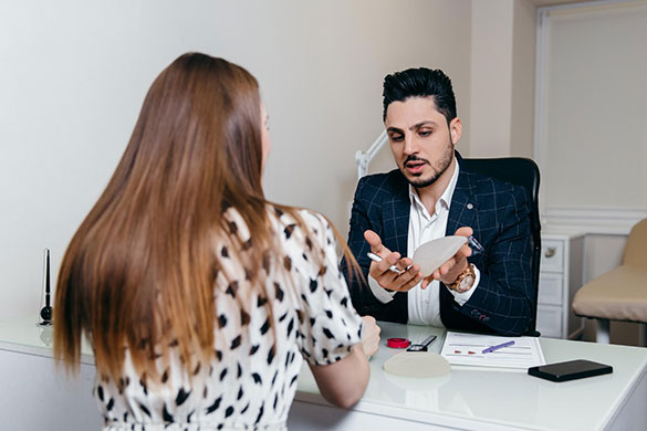 Plastic surgeon showing breast implant to patient