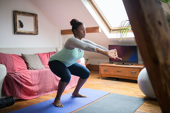 Woman doing lunges with weights on yoga mat in living room