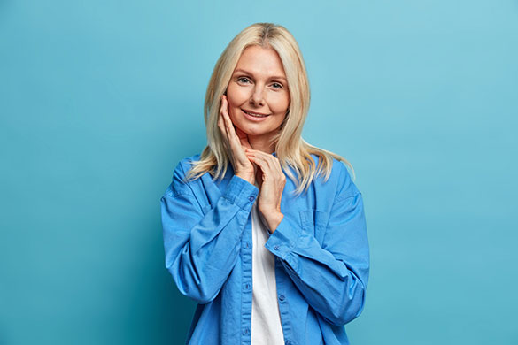 Middle-aged woman smiling while touching her face