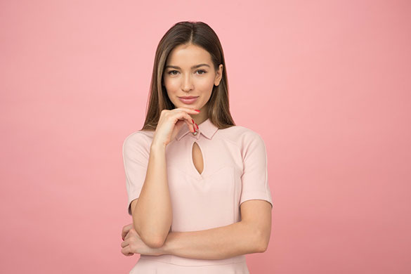 Woman wearing pink top posing into the camera with one hand under chin
